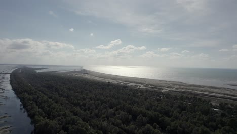 drone-video-over-the-Divjake-Karavasta-nature-park,-frontal-shot-moving-over-the-grove-towards-the-beach-with-the-sunset-on-the-horizon-reflected-in-the-sea
