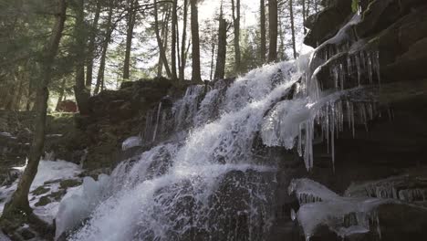 Rosecrans-Falls-waterfall-with-ice-formations-in-a-forest-in-central-Pennsylvania,-pan-downward