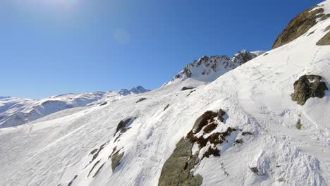 Drohnenschuss-über-Schnee-Und-Felsen,-Der-Eine-Leere-Skipiste-In-Den-Französischen-Alpen-In-Der-Nähe-Des-Skigebiets-Les-Sybelles-Zeigt
