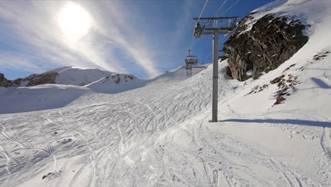 Wide-shot-from-a-skilift-moving-over-a-snowy-mountain-slope-with-off-piste-skiing-tracks-in-the-snow