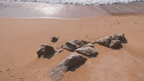 Few-rocks-on-a-pale-cream-color-beach-in-Costa-Brava,-Spain