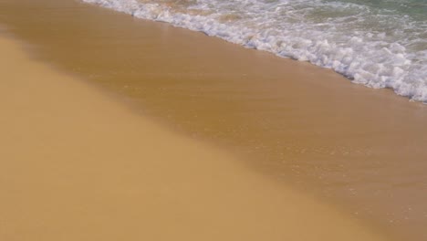 Ocean-waves-rolling-into-golden-sandy-beach-in-slow-motion