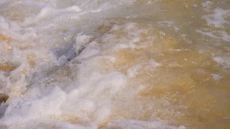 Slow-motion,-clear-water-wave-splashing-into-a-small-rock-at-the-beac