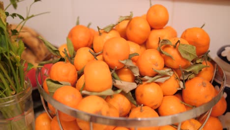 Close-up-view-of-metal-bowl-with-ripe-orange-tangerines,-a-source-of-vitamin-c-on-a-table-in-the-kitchen