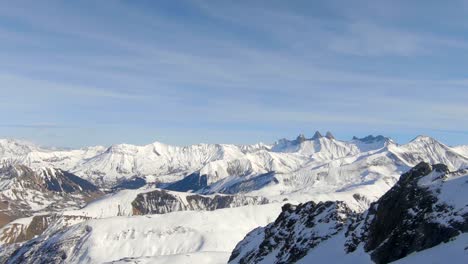 Breiter-Drohnenschuss-Einer-Verschneiten-Winterberglandschaft,-Vorbei-An-Einigen-Felsformationen,-An-Einem-Klaren,-Sonnigen-Tag-In-Den-Französischen-Alpen