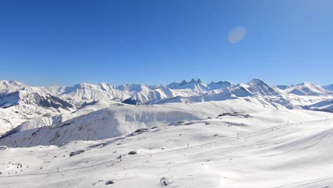 Luftaufnahme,-Die-Sich-Langsam-Hoch-über-Ein-Verschneites-Wintersportgebiet-Mit-Skipiste,-Schlepplift-Und-Skifahrern-In-Der-Ferne-Bewegt