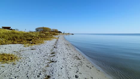 Cloudless-Blue-Skies-Along-a-Stretch-of-Coastline-with-Calm-Waters-in-Kuznica-Poland---Forward-Panning-Shot