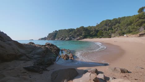 turquoise-water-waves-rolling-into-a-pink-sand-beach-in-Costa-Brava,-Spain