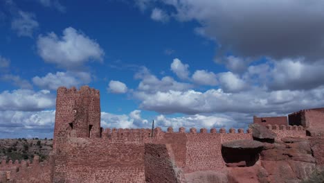 Aerial-drone-view-of-the-Castle-of-Peracense,-in-Teruel-,-built-in-the-X-century-in-the-top-of-a-hill-with-red-sandstone-with-a-changing-nice-sky