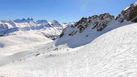 Aerial-shot-over-a-off-piste-ski-slope-with-a-few-skiers-and-many-tracks-of-skiers