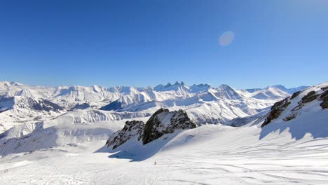 Wide-droneshot-of-a-single-off-piste-skier-in-a-snowy-mountain-landscape-in-the-French-Alps