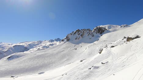 Toma-Aérea-Sobre-La-Ladera-De-Una-Montaña-Cubierta-De-Nieve,-Con-Hermosas-Formaciones-Rocosas