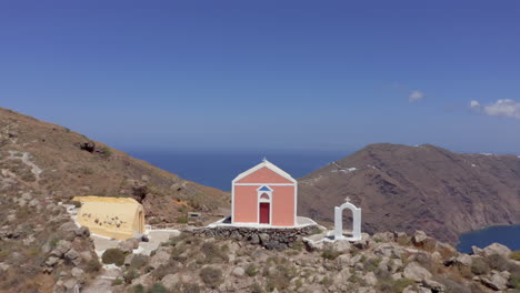 Aerial:-Heading-straight-to-a-small-church-on-a-Greek-island-at-top-of-a-hill