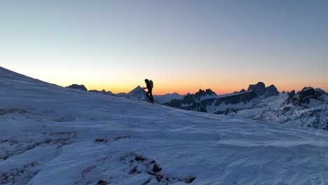 Silhouette-of-a-person-climbing-a-mountain-with-skies-before-sunrise