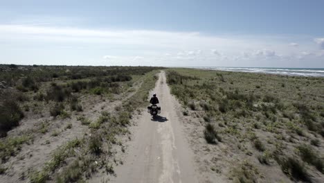 Video-Mit-Drohne-„follow-Me“-Zu-Einem-Am-Strand-Entlang-Fahrenden-Motorradfahrer