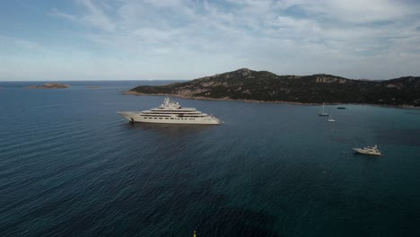 Aerial-orbit-over-a-mega-yacht-of-a-Russian-billionaire-oligarch-anchored-in-a-small-bay-on-the-Emerald-Coast-of-Sardinia
