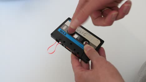woman-repairing-retro-audio-cassette,-winding-tape-by-finger,-white-background,-static