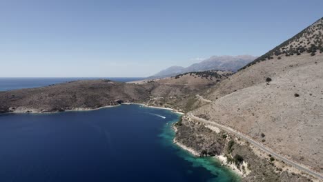 Video-with-a-drone-over-the-turquoise-waters-of-the-Albanian-coast-in-Porto-Palermo,-you-can-see-a-submarine-Bunker-from-the-2-World-War-and-a-boat-sailing