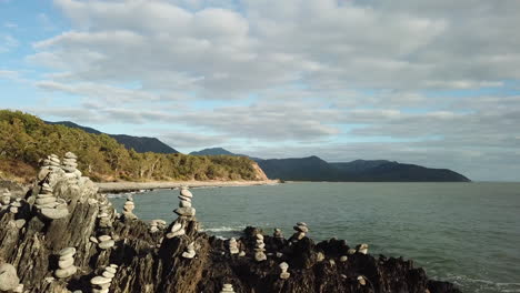 Aerial:-Drone-flying-low-around-stacks-of-rock-cairns-next-to-the-ocean-in-Far-North-Queensland,-Australia