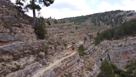 Ruta-del-Barranco-de-la-Hoz-in-Calomarde,-Teruel,-Guadalajara,-Spain---Aerial-Drone-View-of-a-Tourist-Girl-Walking-the-Beautiful-Hike-through-the-Canyon