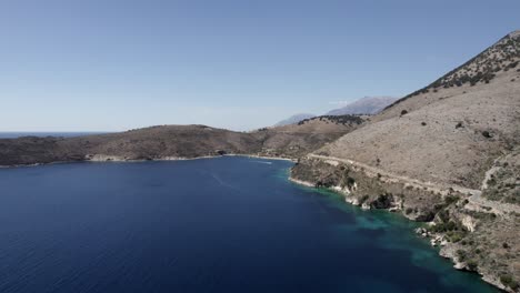 Drone-video-over-the-turquoise-waters-of-the-Albanian-coast-in-Porto-Palermo,-you-can-see-a-submarine-Bunker-from-the-Second-World-War-and-a-boat-sailing