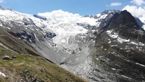 Aerial-flyover-towards-the-Ferpecle-glacier-in-Valais,-Switzerland-on-a-sunny-summer-day,-revealing-the-the-distance-that-the-glacier-has-receded-due-to-melting-as-seen-by-the-moraines