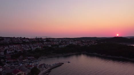 flying-above-croatian-island-Mali-Losinj-and-its-city,-revealing-colourful-sunset