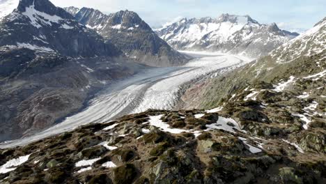 Aerial-flyover-alongside-a-ridge-overlooking-the-Aletsch-Glacier-in-Wallis,-Switzerland,-which-is-the-longest-glacier-of-the-Swiss-Alps-and-Europe