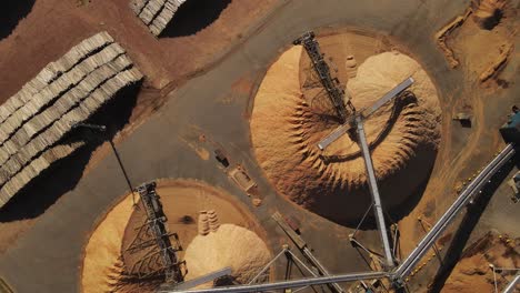 Aerial-top-down-circling-over-piles-of-trunks-and-sawdust-mountains-in-paper-mill-factory