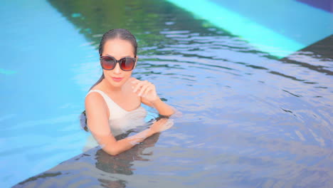 Beautiful-and-sexy-exotic-woman-with-sunglasses-in-swimming-pool-water-on-luxury-tropical-holiday,-slow-motion