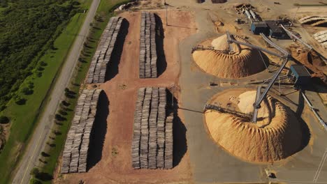 Aerial-view-showing-heap-of-sawdust-and-stacked-piles-of-trunks-in-paper-mill-factory