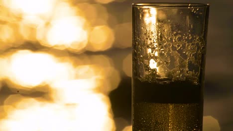 Amber-Light-Ale-Lagerbier-Wird-In-Ein-Glas-Mit-Dem-Meer-Und-Dem-Sonnenuntergang-Im-Hintergrund-Gegossen