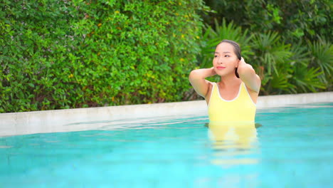 In-a-private-moment,-a-pretty-young-woman,-relaxing-in-a-swimming-pool,-pushes-her-wet-hair-away-from-her-face