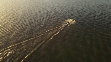Filmische-Drohnenaufnahme-Von-Jet-Ski,-Die-Bei-Sonnenuntergang-In-Zeitlupe-Auf-Dem-Fluss-Fahren