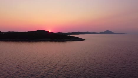Auffliegen-Und-Einen-Farbenprächtigen-Sonnenuntergang-über-Einer-Insel-Mit-Vegetation-Und-Hügeln-Zeigen