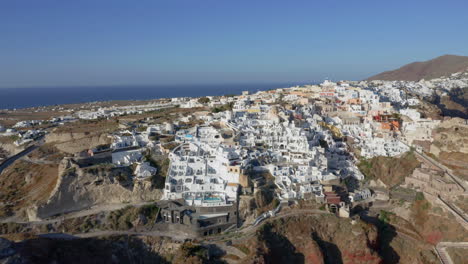 Aerial:-Panoramic-shot-of-houses-and-hotels-at-Oia-Village-In-Santorini,-Greece