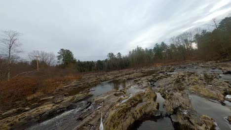 Aerial-flyover-upstream-on-a-Vermont-river-in-fall-over-rocky-creek-bed-in-4k-with-FPV-drone