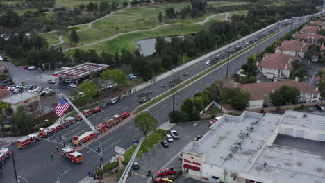 Aerial-drone-of-a-long-funeral-procession,-fire-trucks,-police-cars,-American-flags
