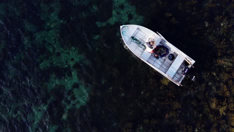 Draufsicht-Auf-Einen-Mann-In-Einem-Weißen-Holzboot,-Das-Auf-Kristallklarem-Wasser-Schwimmt