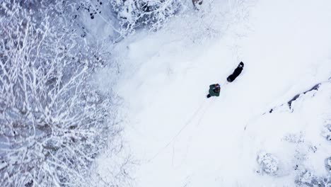 Mann-Und-Hund-Wandern-Im-Winter-Auf-Vereisten-Waldwegen---Luftaufnahme