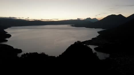 Aerial-View-from-Indian-Nose-over-Lake-Atitlan,-3-volcanoes,-San-Juan-La-Laguna-and-San-Pedro-la-Laguna-just-after-sunrise-in-Guatemalan-highlands