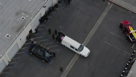 Aerial-drone-over-white-hearse-as-people-load-casket-out-white-hearse