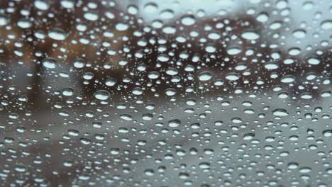 Regentropfen-Auf-Autofensterglas-Mit-Verschwommenen-Stadtautolichtern-Als-Bokeh