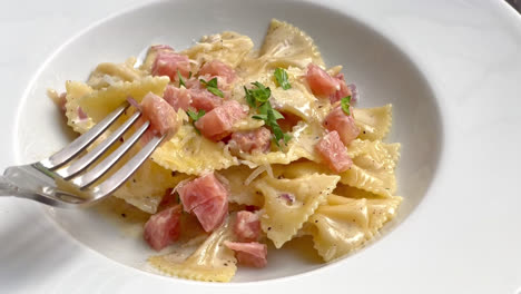 carbonara-farfalle-pasta-with-ham-sausage-on-white-plate