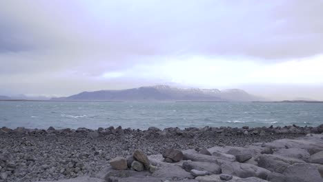 Stone-sea-beach-in-Reykjavik,-Iceland,-with-a-mountain-on-the-horizon
