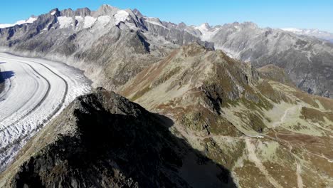 Aerial-view-over-the-Bettmerhorn-next-to-the-longest-glacier-in-the-Alps---the-Aletsch-glacier-in-Valais,-Switzerland-on-a-sunny-summer-afternoon-with-a-panoramic-360-view-of-the-surrounding-peaks