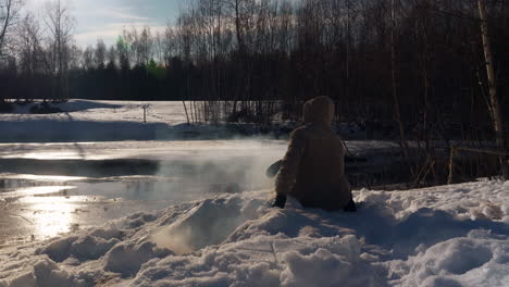 Man-checks-on-campfire-dug-into-snow