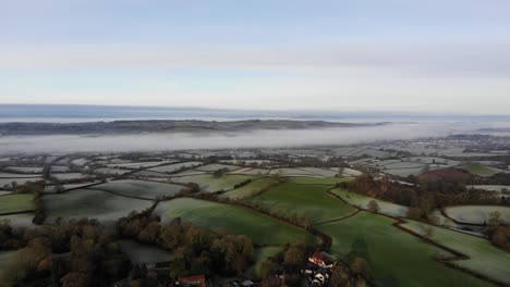 Aerial-panning-left-shot-of-the-River-Otter-valley-in-Devon-England-on-a-frosty-misty-morning