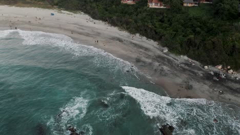 Foamy-Waves-Splashing-On-The-Sandy-Shore-Of-The-Beach-In-Puerto-Escondido,-Mexico---aerial-drone-shot
