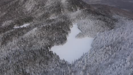 Fliegen-In-Richtung-Zugefrorenen-See-Inmitten-Dichter-Wälder-Im-Winter-Im-Osten-Von-Quebec,-Kanada